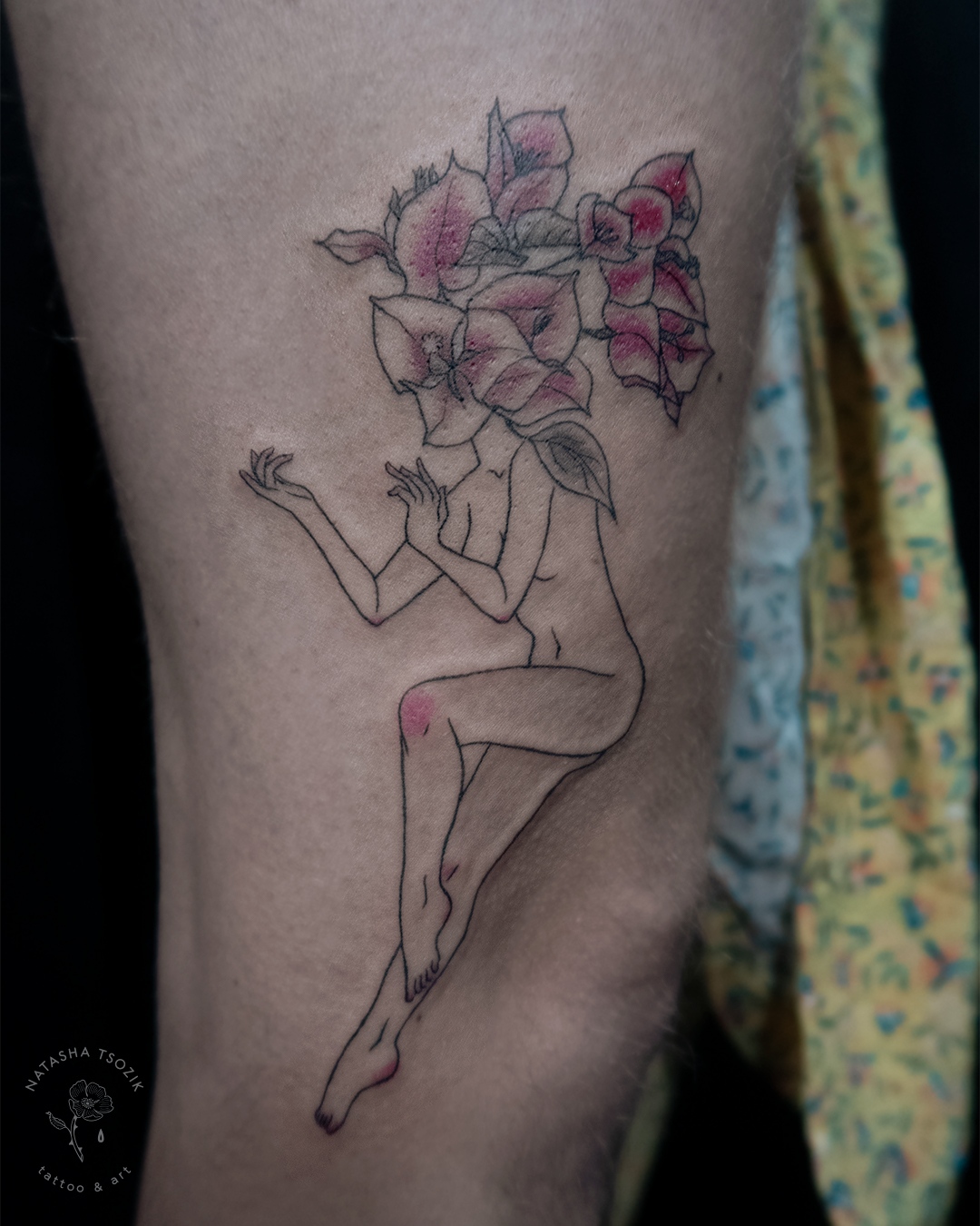 A slightly colored floral tattoo on a leg picturing a flower head girl.