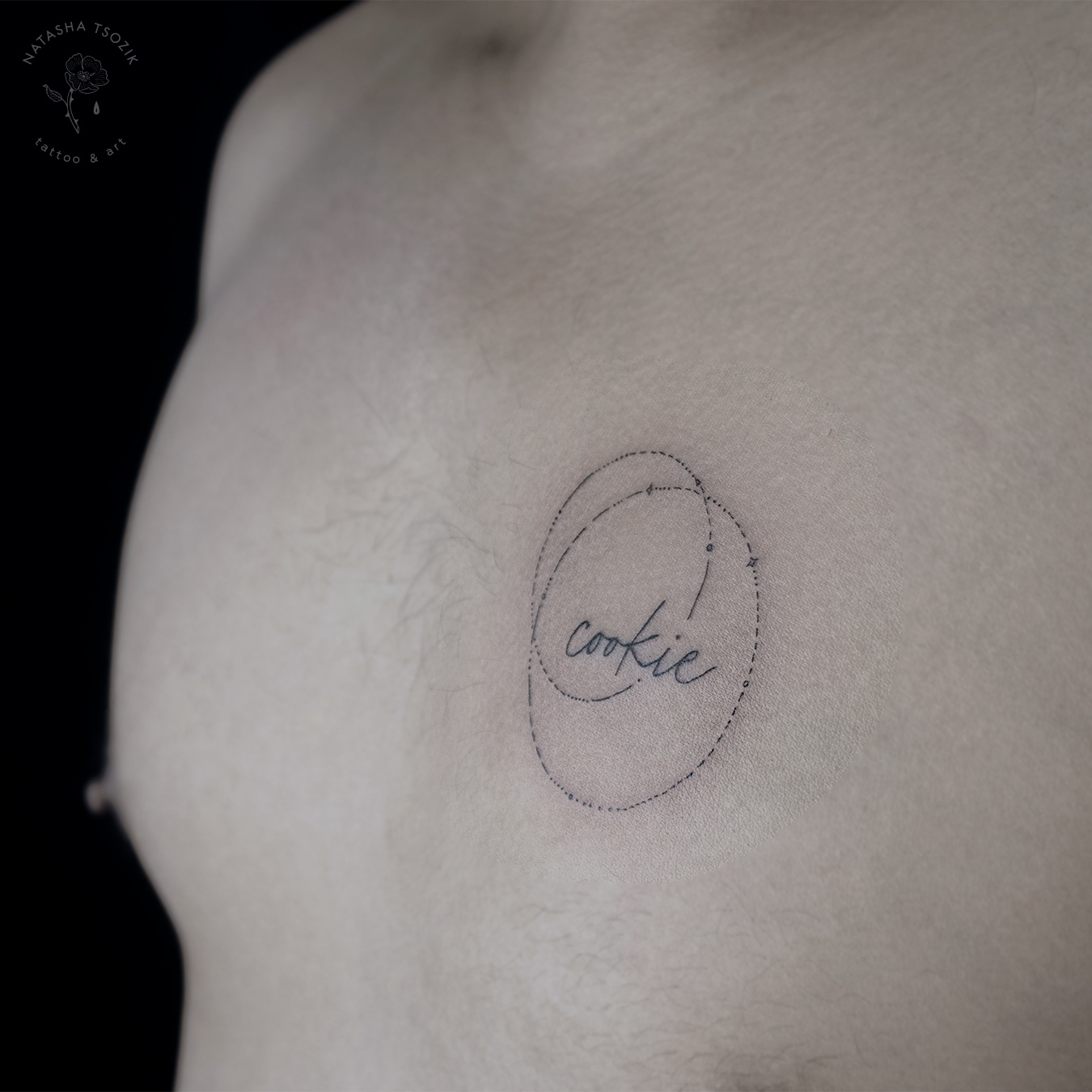 Minimalistic fine line tattoo on a chest picturing circles and an inscription.