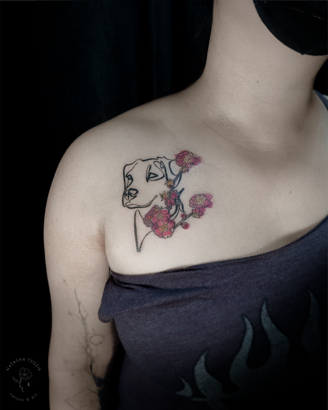 A slightly colored fine line tattoo on a chest picturing a dog's portrait and a plum blossom.