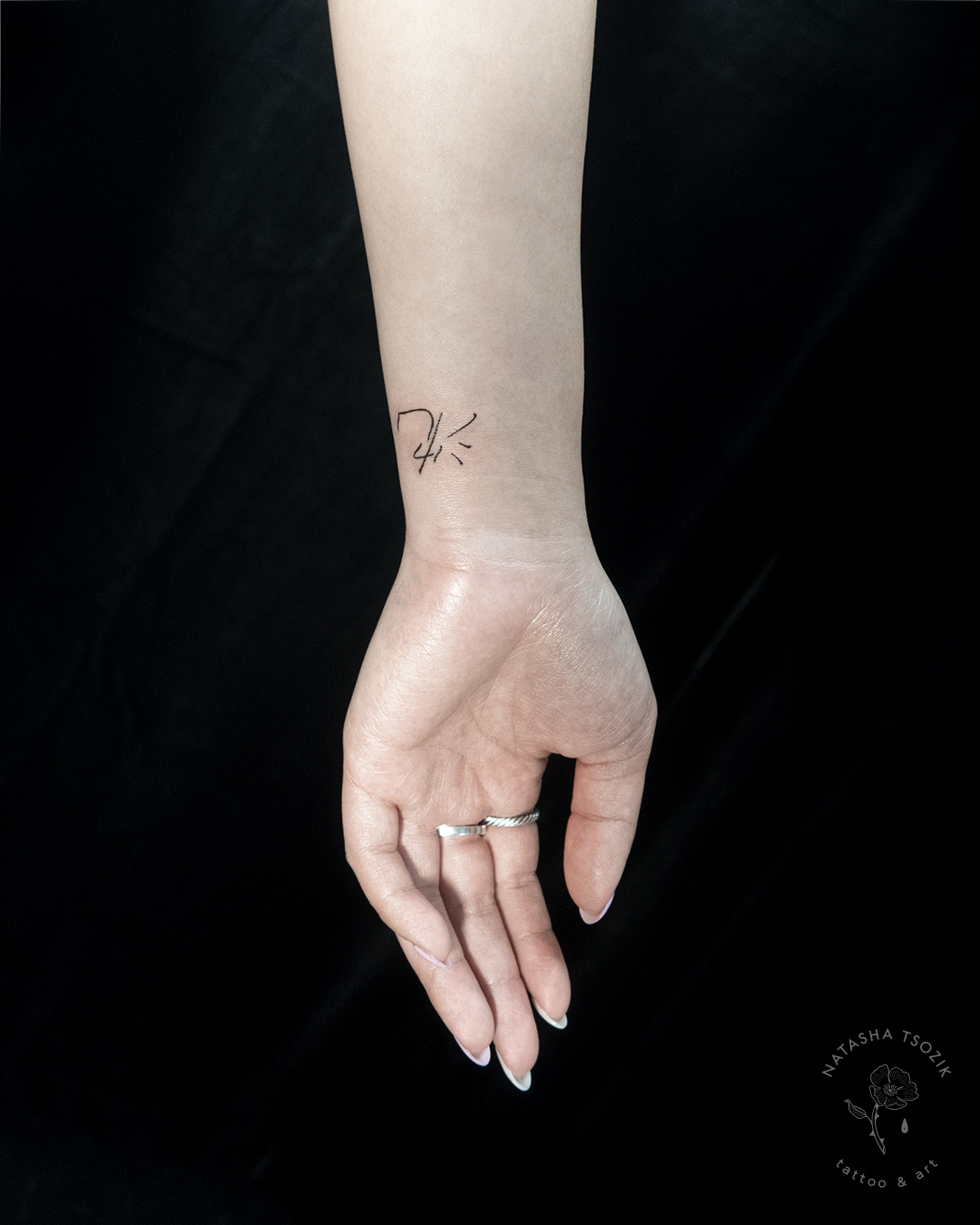 A small signature tattoo on a wrist.