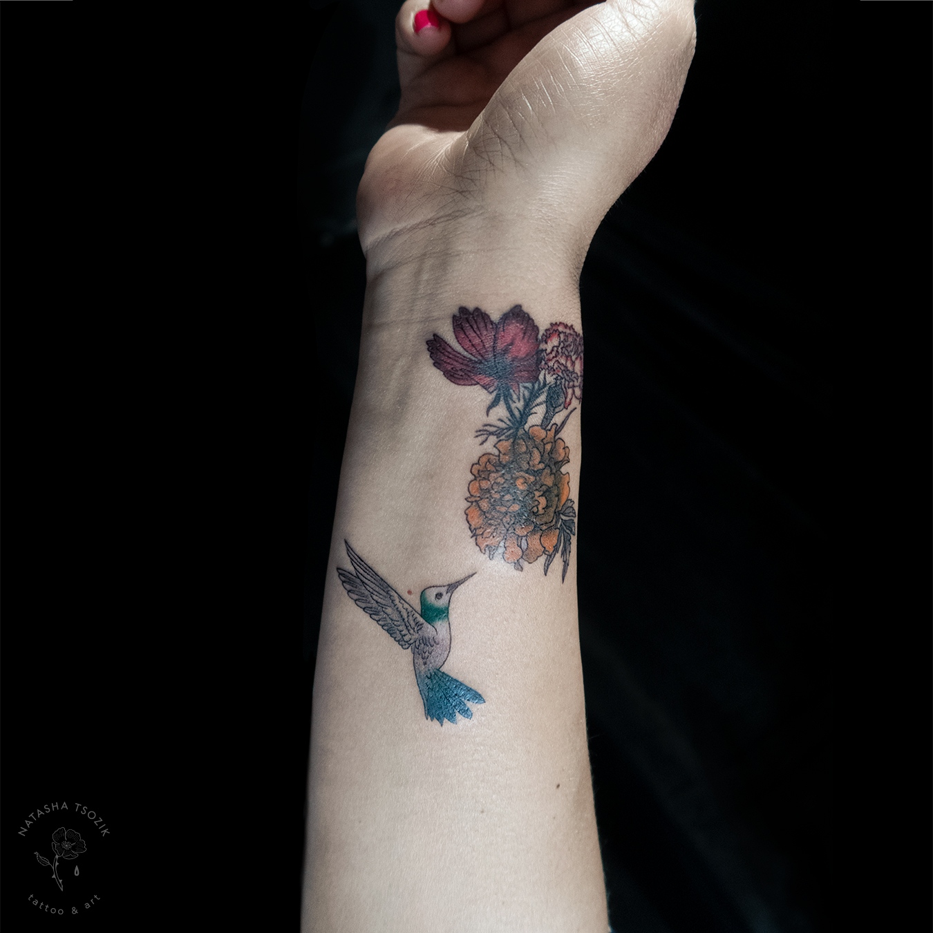 Hummingbird floral tattoo on a wrist.