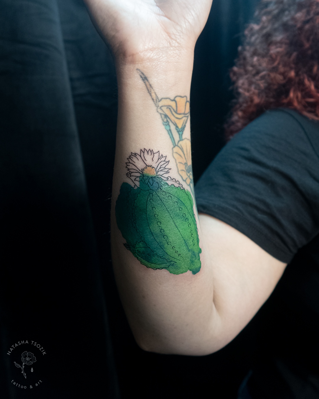 A watercolor cactus tattoo on a forearm.