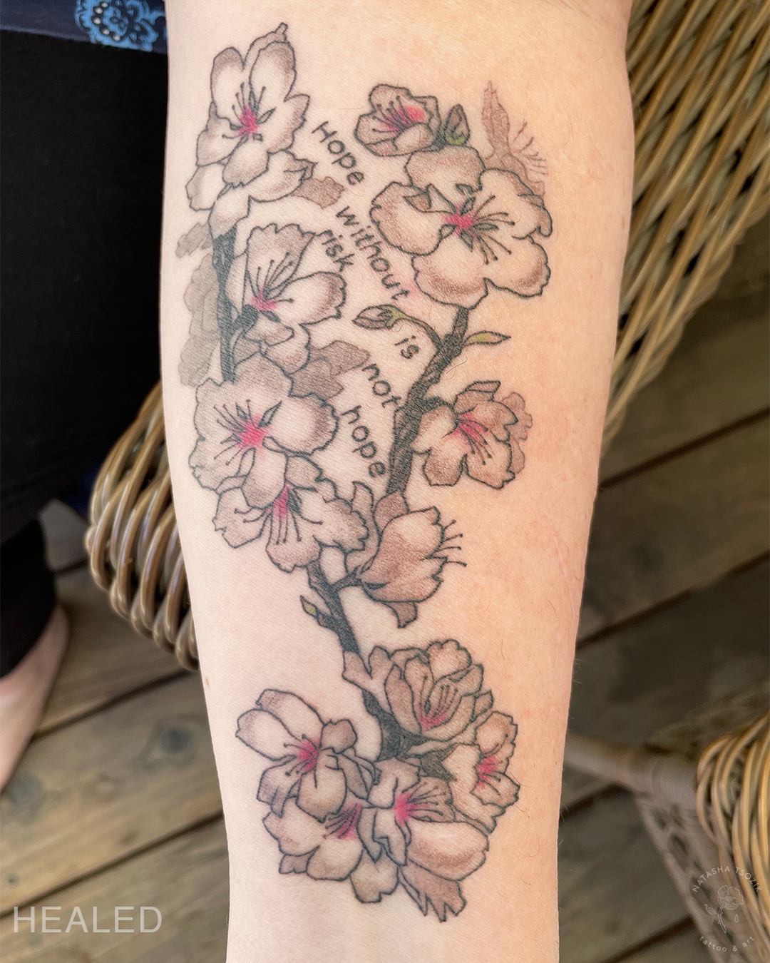 Healed cherry blossom tattoo on a forearm.